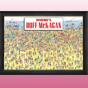Op de afbeelding: Ingelijste print met een drukke strandscène met de tekst "WHERE'S DUFF McKAGAN" in een witte en rode banner. Het kunstwerk toont talrijke mensen op een zandstrand met de oceaan op de achtergrond.