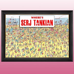 May include: A framed print with a black border showing a busy beach scene. The image is a parody of the "Where's Wally?" series, with the text "WHERE'S SERJ TANKIAN" in red at the top. The beach is packed with many people enjoying the sun and sea.
