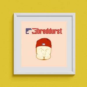 Puede incluir: Una impresión enmarcada en blanco con un fondo melocotón claro. La impresión presenta una ilustración de dibujos animados de una cabeza de pan que lleva una gorra de béisbol roja con un logotipo blanco. El texto "breddurst" está en letras negras sobre la cabeza de pan.