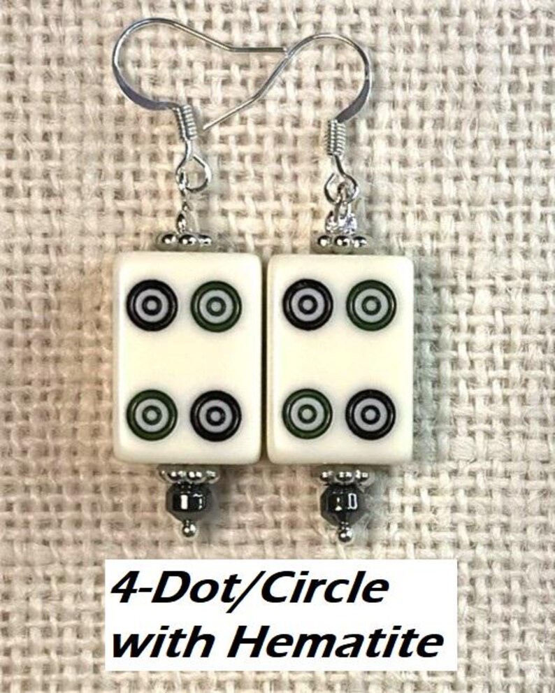 May include: Earrings with ivory-coloured rectangular tiles, each displaying four black and green circles. The earrings have silver hooks and hematite beads. The text "4-Dot/Circle with Hematite" is at the bottom.