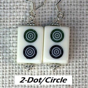 May include: Earrings with rectangular white tiles, each displaying green and black concentric circles. The earrings have silver-coloured hooks and decorative details. The text "2-Dot/Circle" is visible below the earrings.