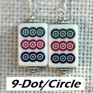 May include: A pair of white Mahjong tile earrings, each featuring three rows of circles in green, red, and black. The earrings have silver-coloured hooks and decorative accents. The text "9-Dot/Circle" is displayed below the earrings.