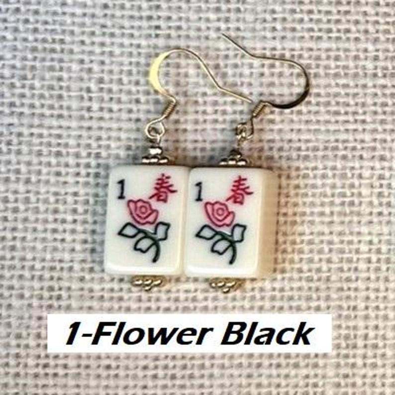 Puede incluir: Pendientes con baldosas rectangulares blancas, cada una con un n&uacute;mero 1 negro, una rosa roja y hojas verdes. Los pendientes tienen ganchos dorados. El texto "1-Flower Black" est&aacute; en la parte inferior.