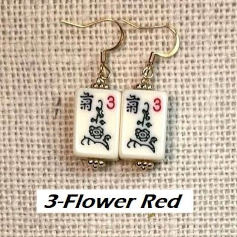 Puede incluir: Pendientes dorados con baldosas blancas rectangulares. Cada baldosa presenta un dise&ntilde;o negro y rojo, que incluye un motivo floral, el n&uacute;mero 3 y caracteres chinos. El texto "3-Flower Red" est&aacute; en la parte inferior.