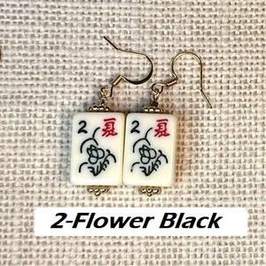 Puede incluir: Pendientes dorados con colgantes rectangulares blancos. Cada colgante muestra un n&uacute;mero 2, un car&aacute;cter chino rojo y un dise&ntilde;o floral negro. El texto "2-Flower Black" est&aacute; en la parte inferior.