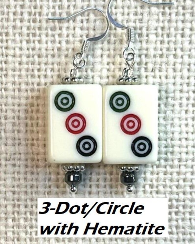 May include: Cream-coloured rectangular earrings with three circles in green, red, and black. The earrings have silver hooks and hematite beads. Text on the image reads "3-Dot/Circle with Hematite."
