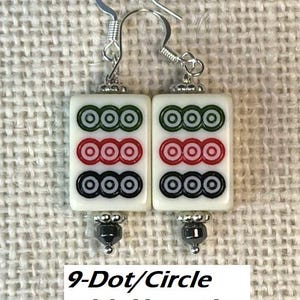 May include: Earrings with white rectangular tiles, each displaying three rows of three circles in green, red, and black. Silver hooks and hematite beads complete the design. The text "9-Dot/Circle with Hematite" is visible at the bottom of the image.