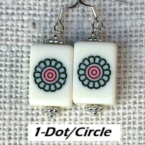 May include: Earrings with rectangular, off-white tiles, each displaying a floral pattern in green, red, and light blue. The earrings have silver-tone hooks and decorative metal elements. The text "1-Dot/Circle" is at the bottom.