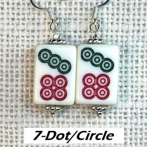 May include: Earrings with a white rectangular tile design, featuring green and red circular patterns, and the text "7-Dot/Circle". The earrings have silver-tone hooks and decorative bead details.