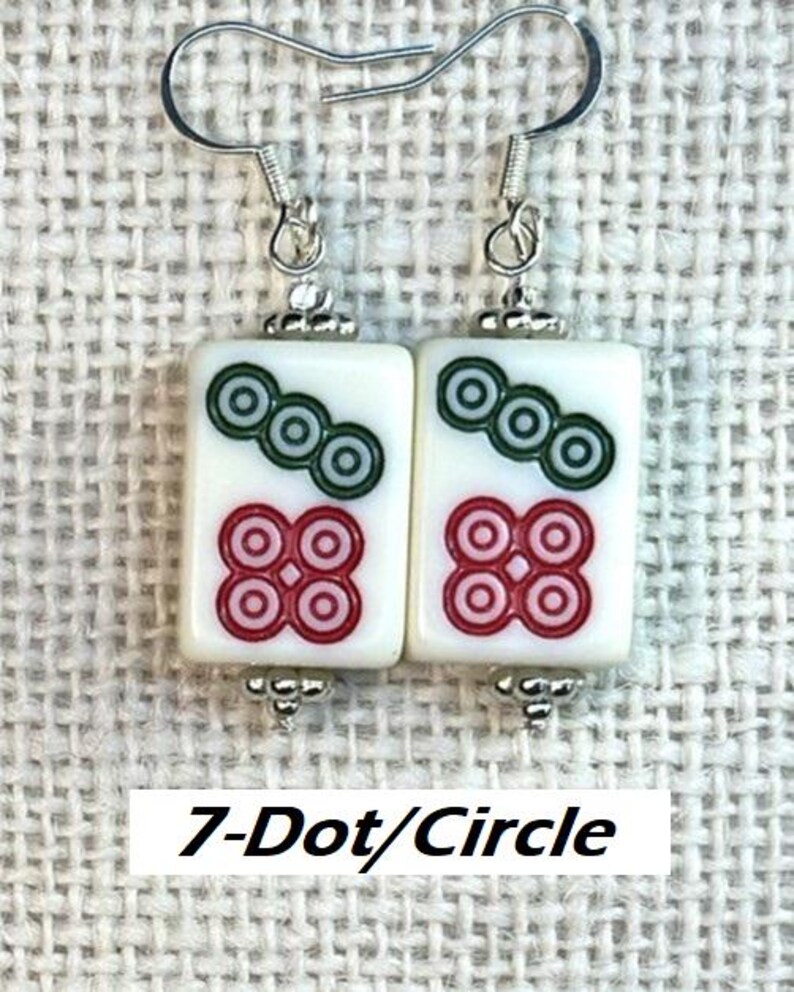 May include: Earrings with a white rectangular tile design, featuring green and red circular patterns, and the text "7-Dot/Circle". The earrings have silver-tone hooks and decorative bead details.