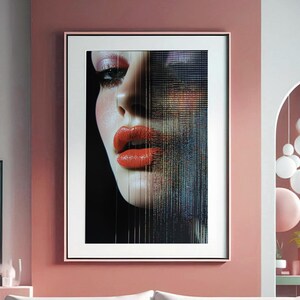 May include: A framed art print featuring a close-up of a face with vibrant red lipstick. The artwork has a modern aesthetic, with a pixelated effect on one side of the face. The print is displayed in a room with a pink and gray color scheme.