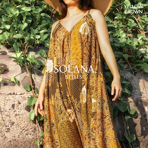 Könnte beinhalten: Ein fließendes, gelb-braun gemustertes Kleid mit dünnen Trägern und V-Ausschnitt. Das Kleid hat ein Blumen- und geometrisches Design. Der Text "SOLANA STYLES" ist auf der Vorderseite zu sehen. Die Worte "YELLOW BROWN" stehen oben rechts.