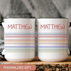 May include: Two white ceramic mugs with black handles and rims. Each mug features the name "MATTHEW" in red, above a colorful geometric pattern. The mugs are labeled "PERSONALIZED GIFT".