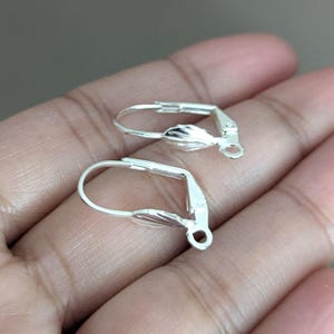 May include: Two silver earring clips with a leaf design. The clips are open and ready to be attached to earrings.