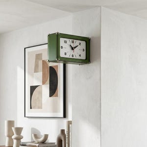May include: A rectangular wall clock with a dark olive green frame and a white face. The clock features black Arabic numerals for 2, 3, 4, 6, 8, 9, 10, and 12, along with black hour and minute hands and a thin red second hand.