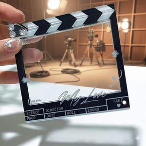 May include: A black and white film clapperboard with the words "Only Love" in cursive. The clapperboard has a clear centre and includes the words "SCENE", "PROD", "DIRECTOR", "DATE", "ROLL", "SOUND", and "TAKE".