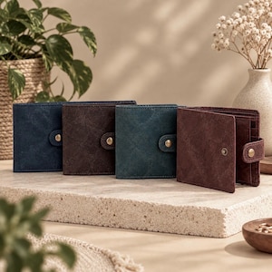 Peut inclure: Quatre portefeuilles pliants en bleu marine, brun foncé, bleu sarcelle et bordeaux. Chaque portefeuille présente une finition texturée, une patte assortie avec un bouton-pression en laiton et des fentes pour cartes visibles à l'intérieur.