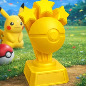 Peut inclure: Un trophée jaune avec un design de Poké Ball et trois étoiles sur le dessus. Une figurine Pikachu et une Poké Ball sont à l'arrière-plan sur un champ herbeux. Des confettis tombent du ciel.