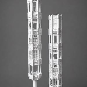 Peut inclure: Deux structures blanches, hautes et élancées, en forme de tour, avec des motifs géométriques ajourés et des détails architecturaux. La structure la plus haute présente un toit et repose sur une base hexagonale, tandis que la plus courte est cylindrique.