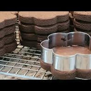Peut inclure: Des piles de biscuits en forme de fleur, fraîchement cuits et brun foncé, sont posées sur une grille. Un emporte-pièce argenté en forme de fleur est à côté d'un biscuit. Les biscuits semblent être au chocolat.
