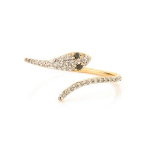 May include: A gold snake ring with black and white diamonds. The snake is curled around the finger and has a diamond-encrusted head.