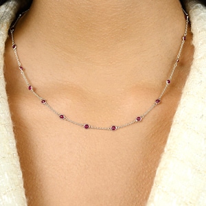 Puede incluir: Un collar de cadena de plata con pequeñas piedras preciosas redondas de color rojo.