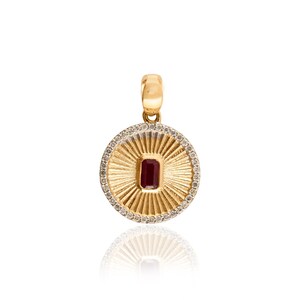 May include: A gold pendant with a circular design. The center features a rectangular, dark red gemstone. The pendant is surrounded by a ring of small, clear stones and a sunburst pattern. The bail is also gold.