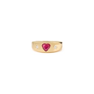 Peut inclure: Une bague en or avec un rubis en forme de cœur au centre, flanquée de deux petites pierres précieuses rondes et claires. La bague a une finition lisse et polie et une large bande.