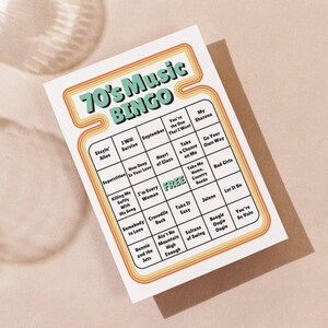 May include: A retro-style bingo card with the text "70's Music BINGO" in a teal and orange design. The card features a grid with song titles from the 1970s, including "Stayin' Alive" and "Jolene". The card is on a neutral background.