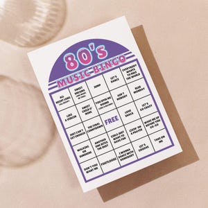 May include: A white 80's Music Bingo card with a purple and pink header. The bingo card features song titles from the 1980s, including "Sweet Dreams" and "Like a Virgin". The card is on a brown envelope.