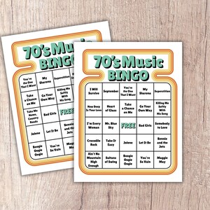 May include: Two retro-style bingo cards with a 70's theme. The cards feature a colorful design with the text "70's Music BINGO" at the top. Each card has a grid of song titles, including "You're the One That I Want" and "Take a Chance on Me".