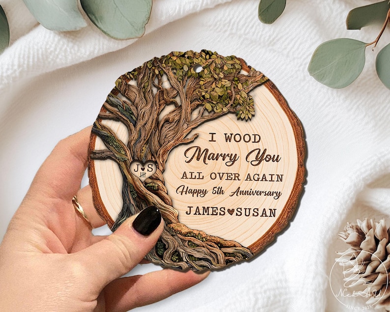 Op de afbeelding: Houten boomschijf ornament met een uitgesneden boomontwerp en de tekst "I Wood Marry You All Over Again Happy 5th Anniversary James & Susan". Het ornament is rond en heeft een natuurlijke houtnerf.