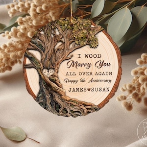 Op de afbeelding: Houten boomstam ornament met de tekst "I Wood Marry You All Over Again Happy 5th Anniversary JAMES SUSAN". Het ornament heeft een gedetailleerd boomontwerp met een hart en initialen.