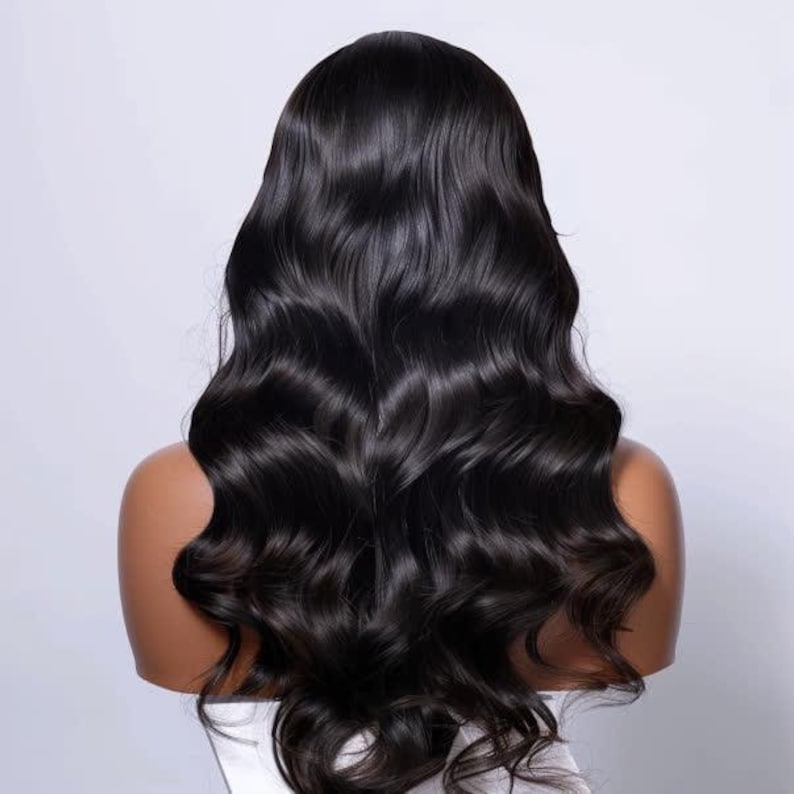 May include: A black, wavy wig with long, flowing hair. The wig is styled with loose curls and has a natural-looking shine. The hair cascades down the back, creating a voluminous and elegant appearance. The wig is shown on a mannequin head.