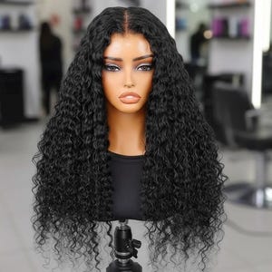 以下が含まれることがあります： マネキンの頭にスタイリングされた黒い巻き毛のかつら。 かつらは深い分け目と長くボリュームのあるカールが特徴です。 マネキンは黒い三脚スタンドに取り付けられており、黒いトップスを着ています。 背景はぼやけたサロンの設定です。