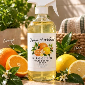May include: A clear glass spray bottle with a white trigger nozzle containing a yellow liquid. The label reads Organic & Natural Maggie's Multi-Purpose Spray Citrus Blend Hand Made 500ml, featuring illustrations of oranges, lemons, and white blossoms.