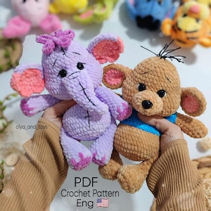 Może przedstawiać: Dwa ręcznie robione szydełkowe pluszaki: lawendowy słoń z różową kokardą i uszami oraz brązowy miś z niebieską koszulą. Tekst "PDF Crochet Pattern Eng" jest widoczny na dole zdjęcia.