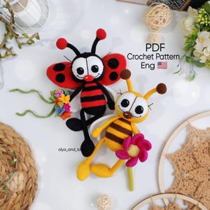 Può includere: Due giocattoli di insetti all'uncinetto: una coccinella e un'ape. La coccinella ha un corpo rosso e nero, che tiene un piccolo bouquet. L'ape ha un corpo giallo e marrone, che tiene un fiore rosa. Il testo "PDF Crochet Pattern Eng" è incluso.