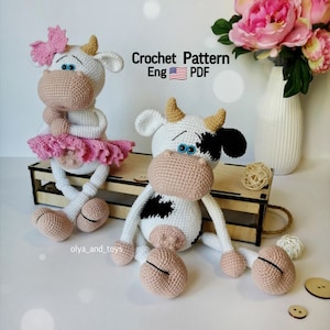 Może przedstawiać: Wzór na szydełku na dwie amigurumi krowy. Jedna krowa ma na sobie różową baletkę i różową kokardkę. Druga krowa jest czarno-biała. Wzór jest dostępny w języku angielskim i jest plikiem PDF do pobrania. Crochet Pattern Eng PDF