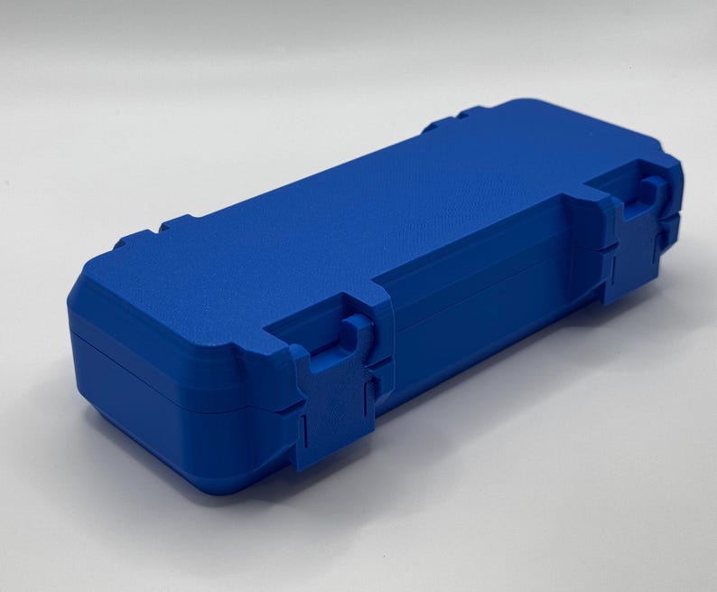 K&ouml;nnte beinhalten: Eine leuchtend blaue, rechteckige Box mit strukturierter Oberfl&auml;che. Die Box hat einen Klappdeckel und zwei sichere Verschl&uuml;sse an der Vorderseite. Sie dient zum Schutz und zur Aufbewahrung.