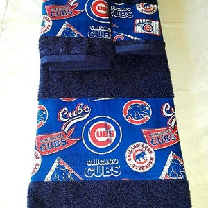 May include: A set of three blue towels with a Chicago Cubs theme. The towels feature a variety of Cubs logos and graphics, including the team's iconic "C" logo, a baseball, and a bear. The towels are made of a soft, absorbent material and are perfect for any Cubs fan.