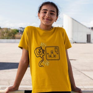 Könnte beinhalten: Ein gelbes T-Shirt mit einer schwarzen Grafik eines Steckers und einer Steckdose mit Blitzen.