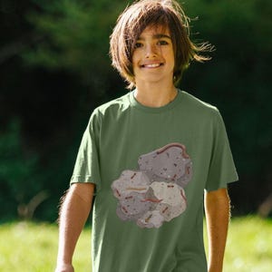May include: A young person wearing a green t-shirt with a graphic of a rock formation with ants and other insects.