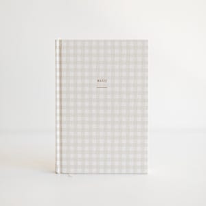 May include: A hardcover notebook with a light gray and white gingham pattern. The word "notes" is printed in a small, brown font on the front cover. The notebook has a white ribbon bookmark.