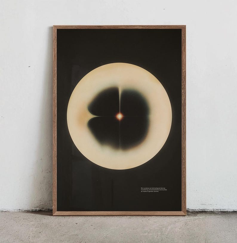 May include: A framed art print featuring an abstract design. The artwork showcases a large, off-white circular shape against a black background. Within the circle, a dark, symmetrical pattern is visible, with a central, glowing point. The frame is made of wood.