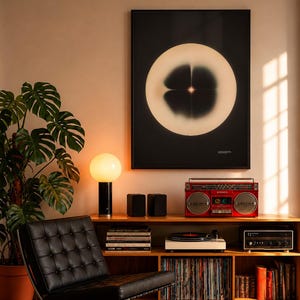 May include: A mid-century modern living room setup featuring a black leather chair, a wooden cabinet with a record player and a red boombox. A large abstract art print hangs above the cabinet. A monstera plant and a table lamp with a round white shade are also present.