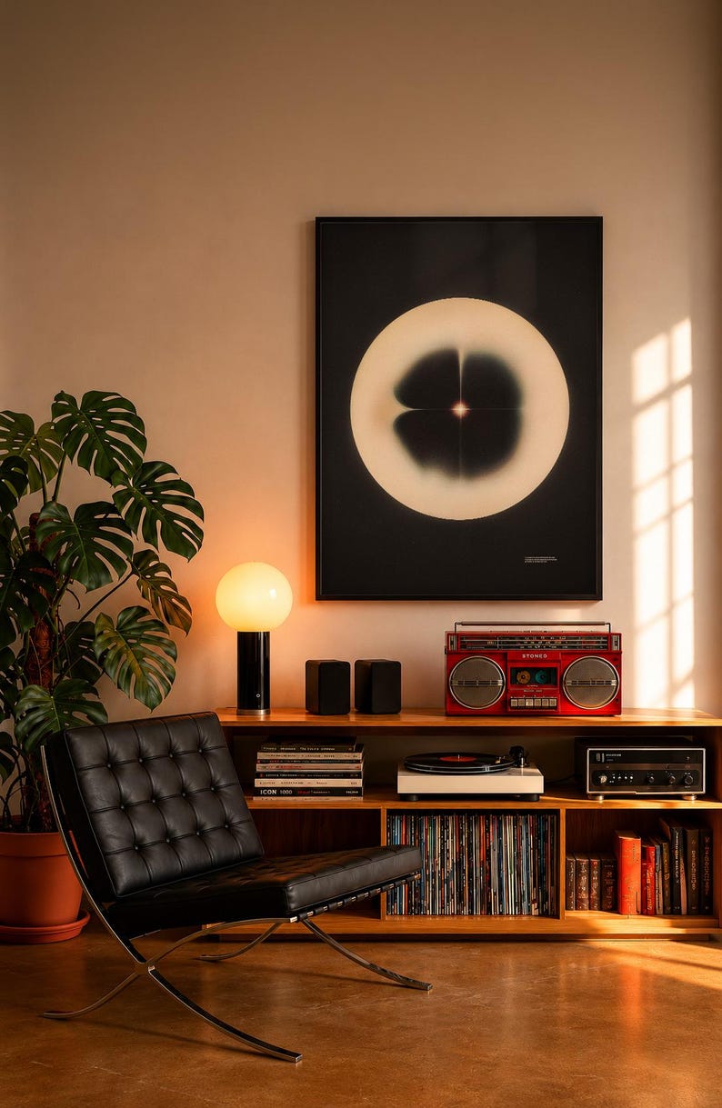 May include: A mid-century modern living room setup featuring a black leather chair, a wooden cabinet with a record player and a red boombox. A large abstract art print hangs above the cabinet. A monstera plant and a table lamp with a round white shade are also present.