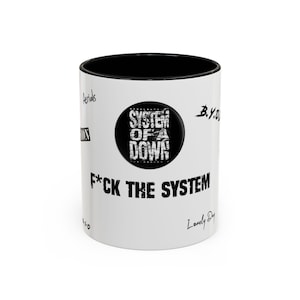 May include: White ceramic coffee mug with a black rim and handle. The mug features a black and white graphic of the band System of a Down's logo and the text "F*CK THE SYSTEM".