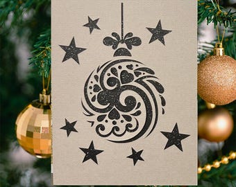 May include: A beige Christmas card featuring a black ornament design with glitter accents and surrounding stars. The card is hanging on a Christmas tree with gold ornaments and a pine cone.