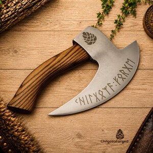 K&ouml;nnte beinhalten: Ein Handbeil mit einem geschwungenen Holzgriff und einer breiten, silberfarbenen Metallklinge. Die Klinge zeigt ein eingraviertes Tannenzapfen-Symbol und eine Zeile mit Runenschrift. Der Text ChilgozaForged und ein Tannenzapfen-Logo stehen unten.